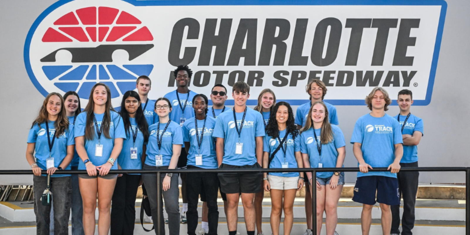 Group in blue Student TRACK t-shirts in front of Charlotte motor Speedway Sign