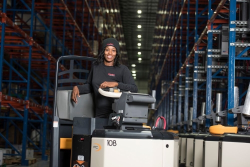 Women in manufacturing: woman operating machinery in warehouse