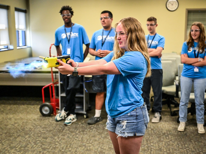 Female in Student Track shirt trying a laser gun